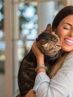 Young beautiful woman smiling and cuddling cat with love at home