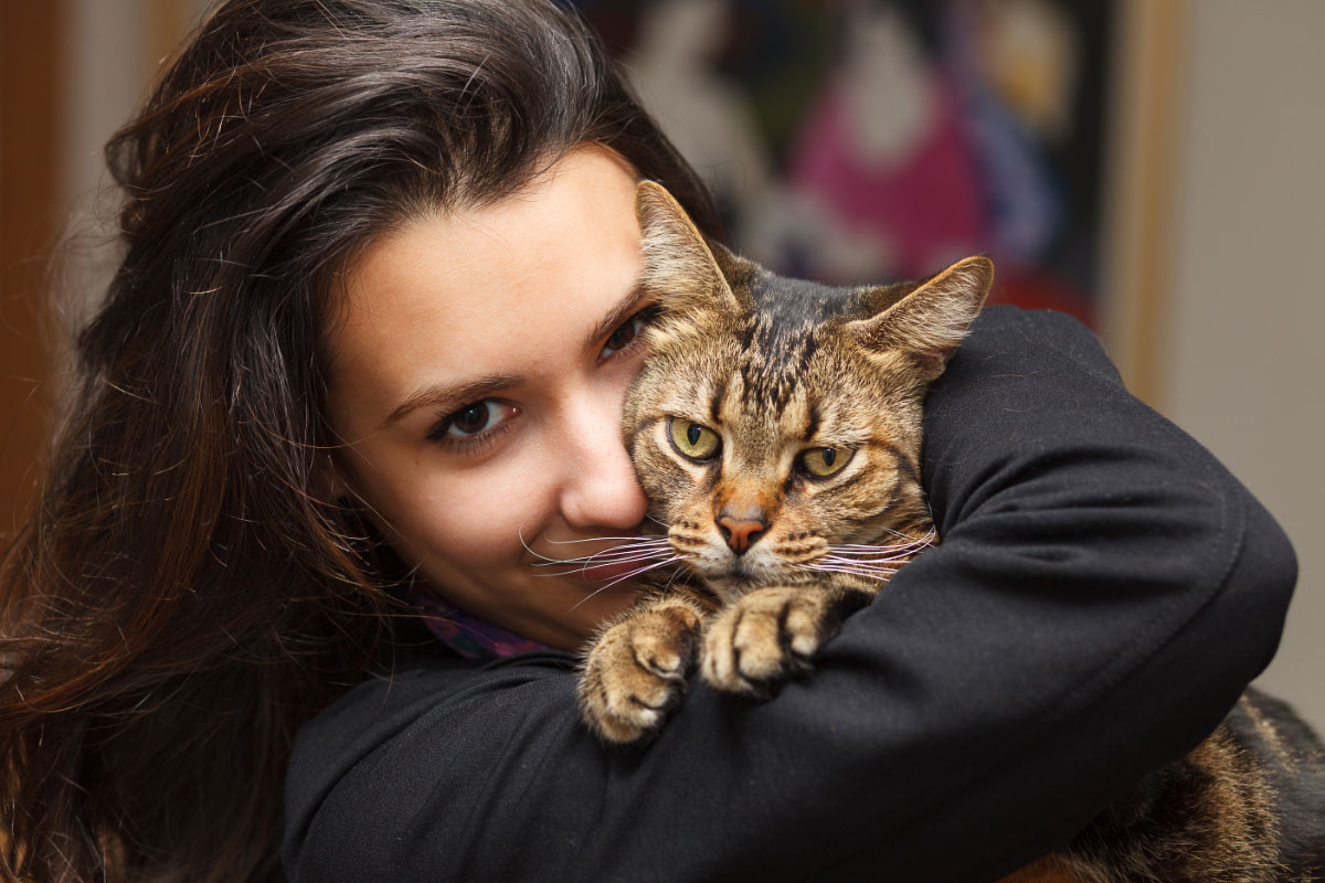 Woman cuddling a Tabby cat.